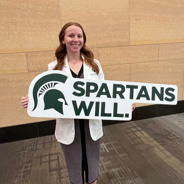 Jenna Koelsch holding a Spartans Will sign.